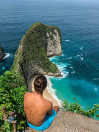 Rear view of shirtless man looking at sea