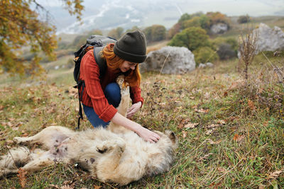 Rear view of woman with dog on grass