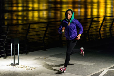 Full length of woman running on footpath at night