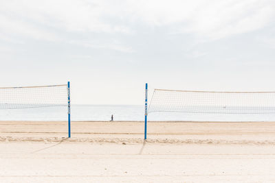 Volleyball net at beach against sky