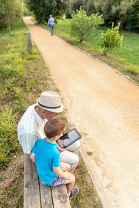 Grandson teaching digital tablet to grandfather while sitting in public park