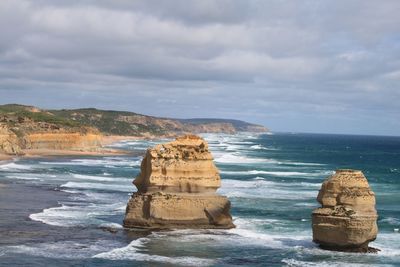 Rock formation on sea shore against sky