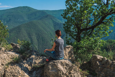 Man sitting on rock looking at mountain