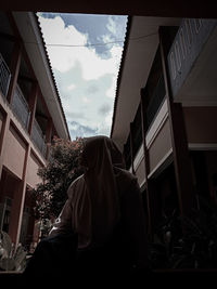 Low angle view of man outside house against sky