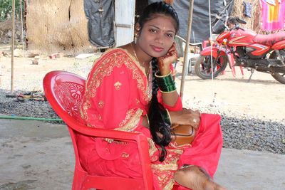 Woman holding red while sitting outdoors