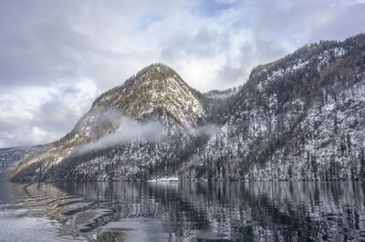 Scenic view of lake by snowcapped mountains against sky