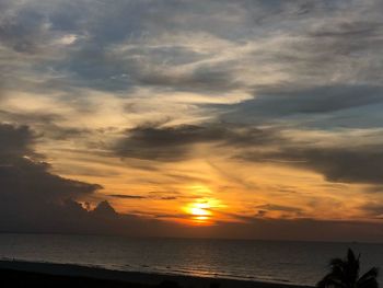 Scenic view of sea against dramatic sky during sunset