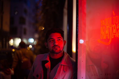 Portrait of young man standing in city at night