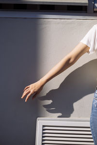 Midsection of woman reading book against wall