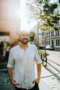 Portrait of smiling man standing on street against buildings in city