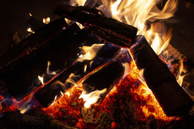 Close-up of embers and burning wood in a fire bowl at night