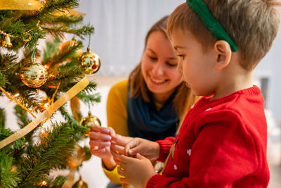 Smiling mother and son decorating christmas tree