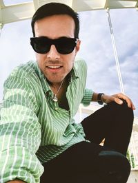 Portrait of man wearing sunglasses sitting outdoors