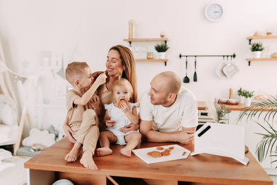 Happy big family of mom dad two kids cooking together and having fun in the kitchen at home