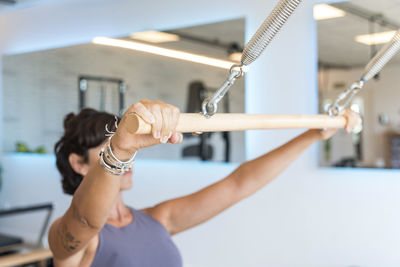 Slim adult female stretching body on modern reformer during pilates training in gym
