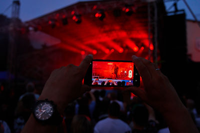 Person standing in front of stage, recording live music concert on smartphonermance