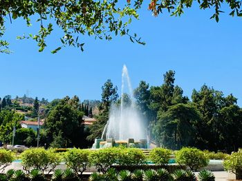 Fountain in park against blue sky