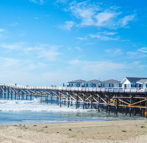 Pier on beach against blue sky