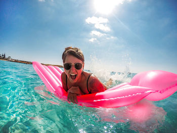 Portrait of cheerful young woman on pool raft in sea