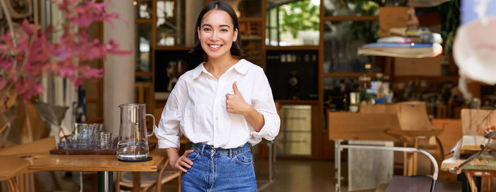 Portrait of young woman standing in cafe