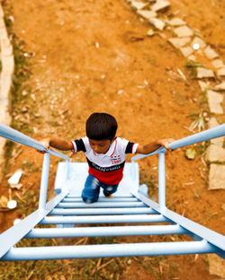 Rear view of boy playing on slide at playground