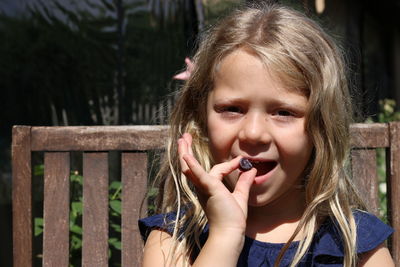 Close-up portrait of girl eating fruit outdoors