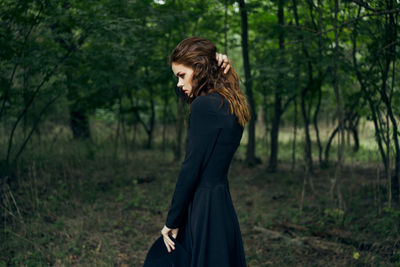 Young woman standing against trees