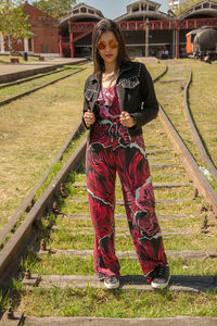 Portrait of woman wearing sunglasses standing on railroad track