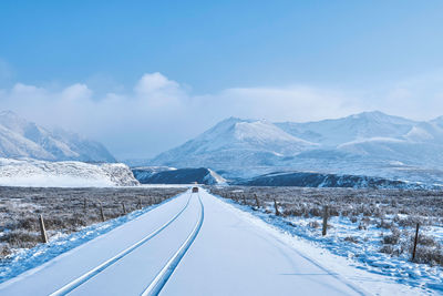 Diminishing perspective of snow covered road against sky