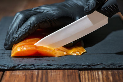 Cropped hand of person holding knife on table