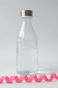 Close-up of glass bottle on table against wall