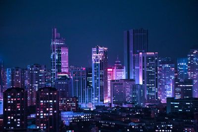 Illuminated buildings in city against sky at night