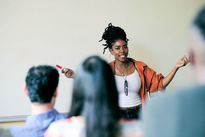 Portrait of confident teacher gesturing while teaching students in language class