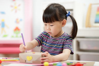 Cute girl sitting on table at home