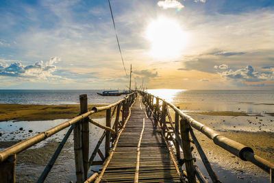 Pier over sea against sky during sunset