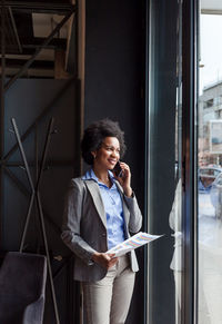 Businesswoman talking on mobile phone while holding graph