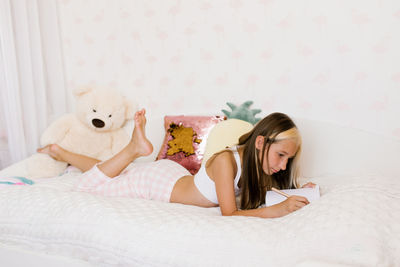 Young woman with teddy bear on bed at home
