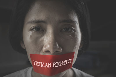 Close-up portrait of crying woman with duct tape on mouth