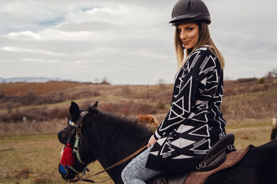 Young woman riding horse on field