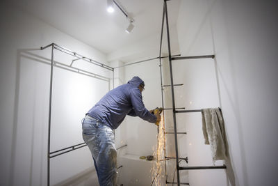 Side view of man working on wall