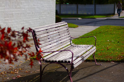 Empty bench in park against wall