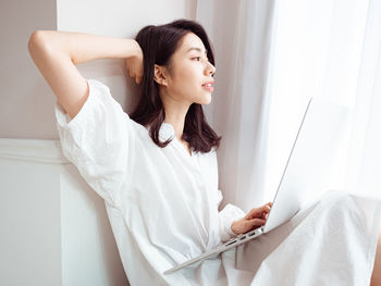 Young asian woman stretching her arms after using laptop.