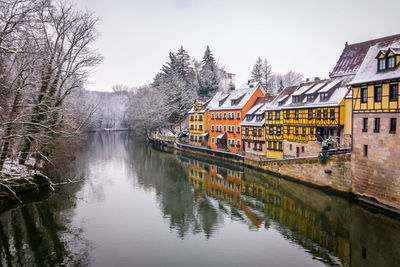 Buildings by river against sky