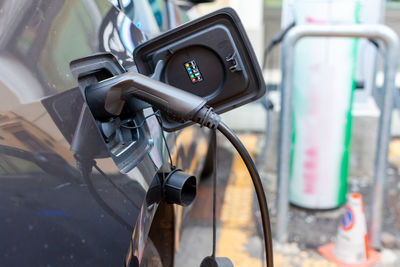 A cable is recharging an electric car at the charging station