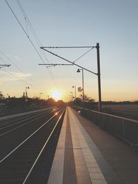 Empty railroad station platform against sky during sunset