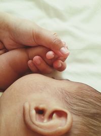 Cropped image of hand holding sleeping babys hand