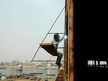 Welder working at construction site against clear sky