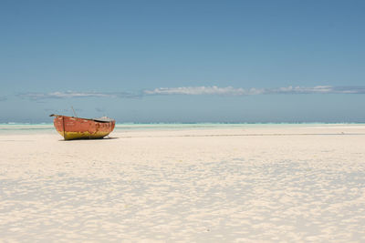 Boat moored on beach against sky