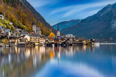 Scenic view of lake by buildings and mountains against sky