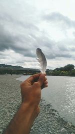 Close-up of hand holding sea against sky